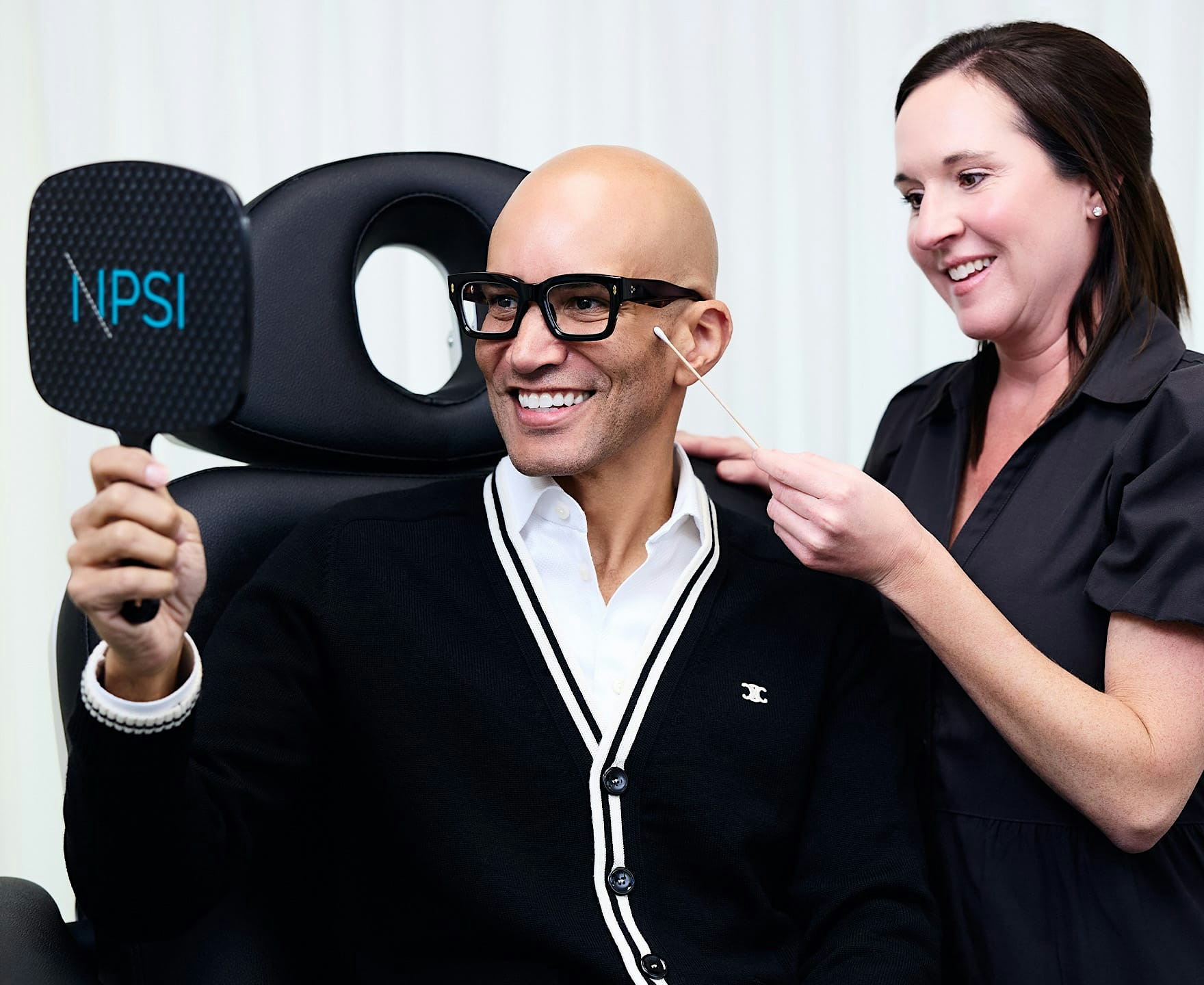 man smiling into hand mirror