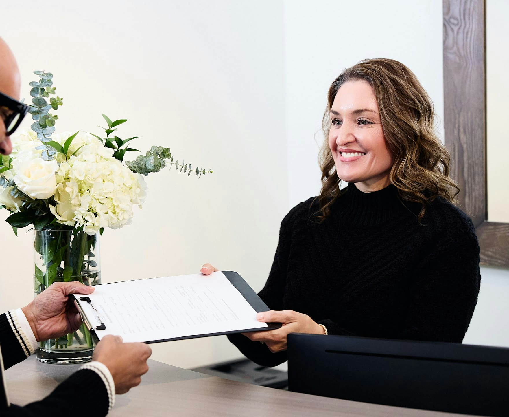Woman smiling while handing in clipboard