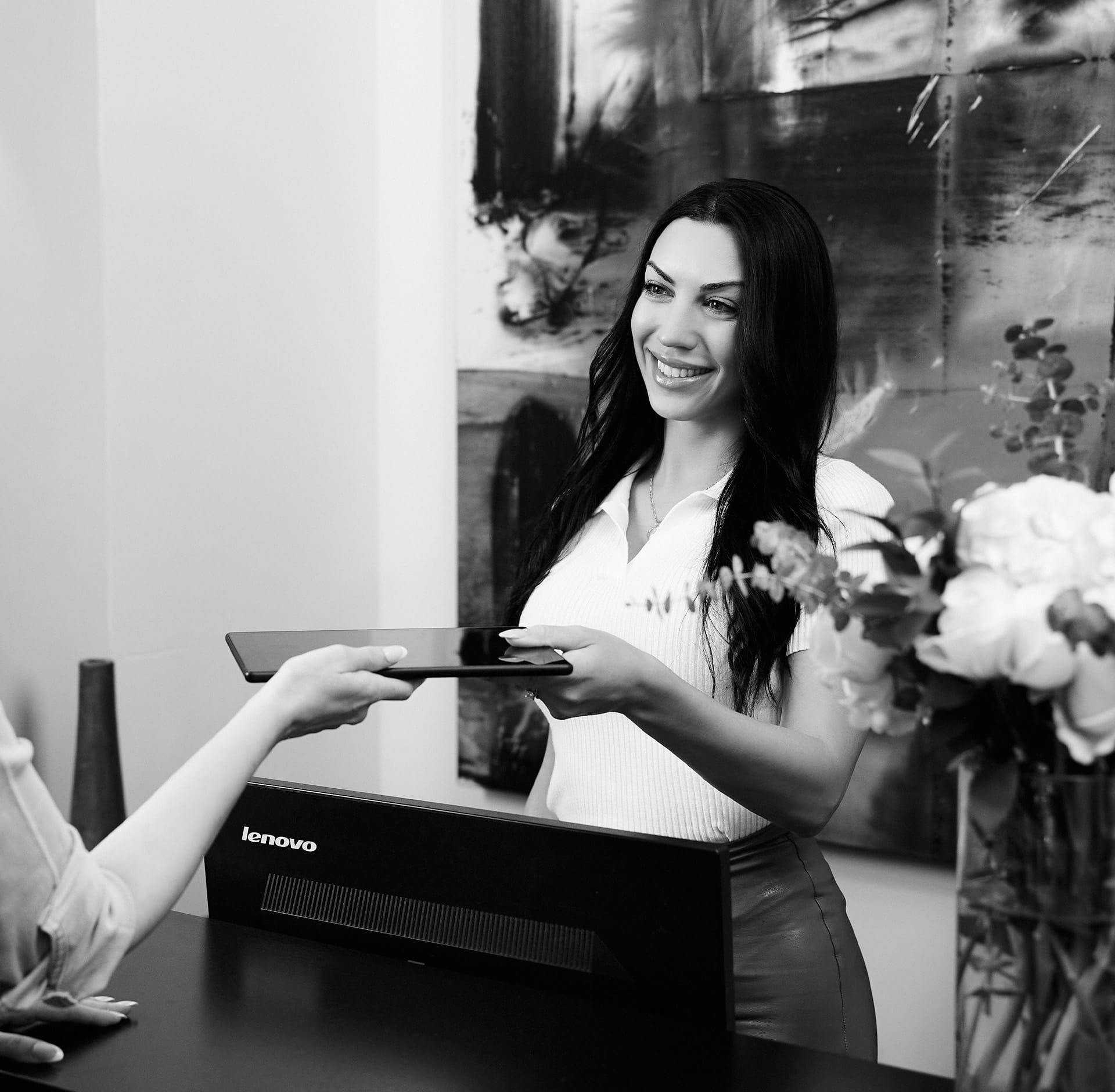 Woman handing tablet to staff member