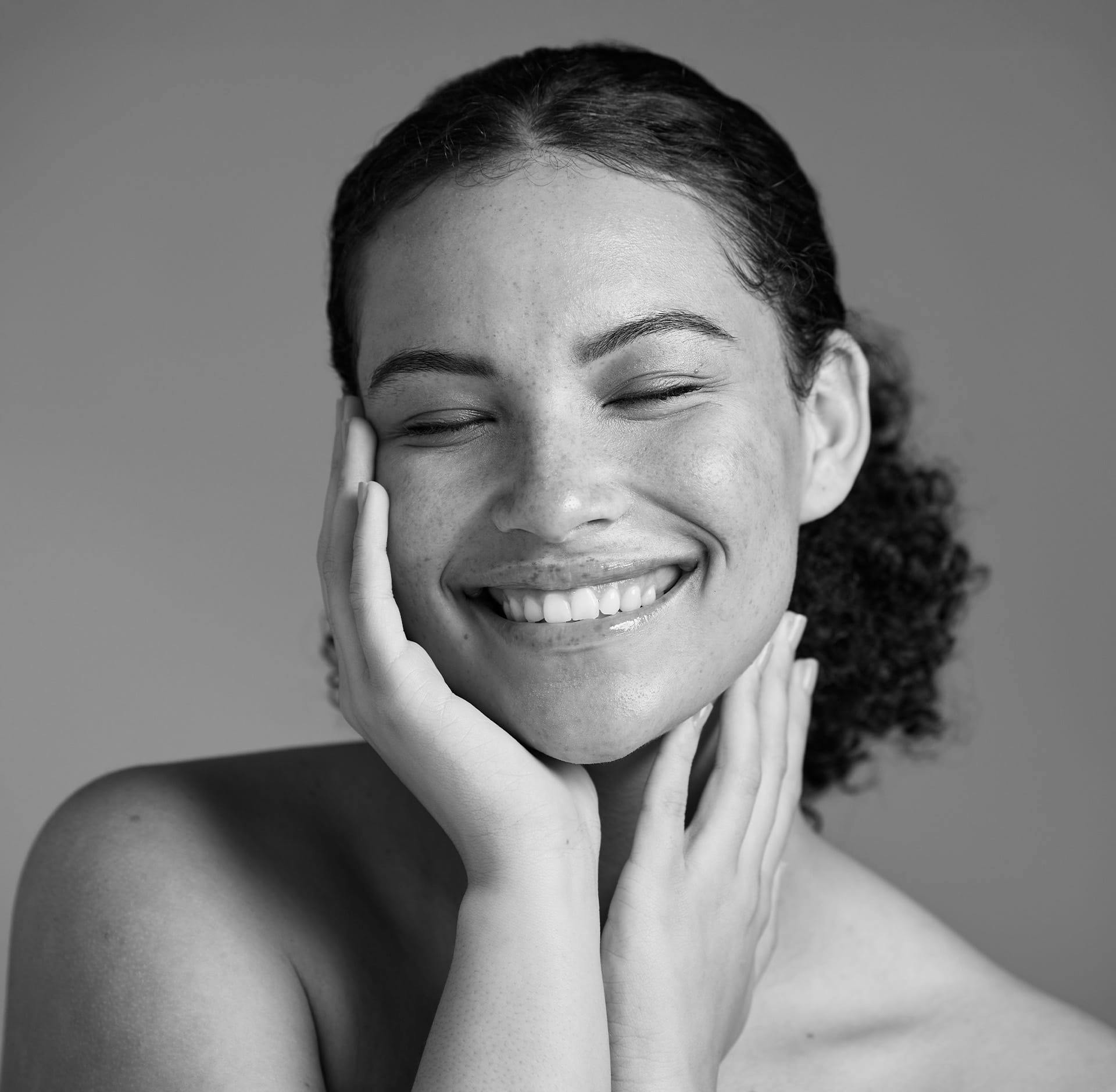 woman smiling and holding her face