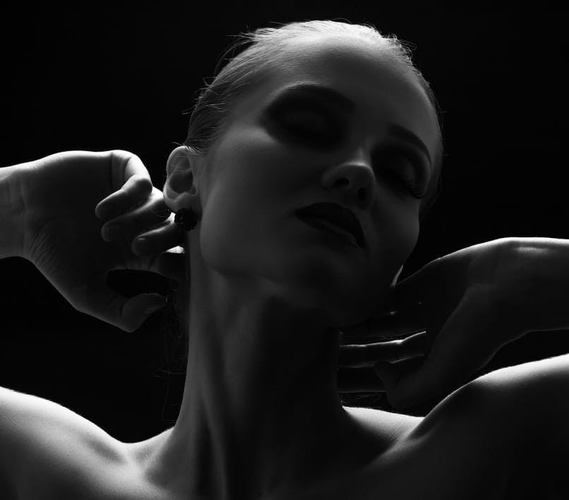 black and white image of a woman with her arms raised up near her head