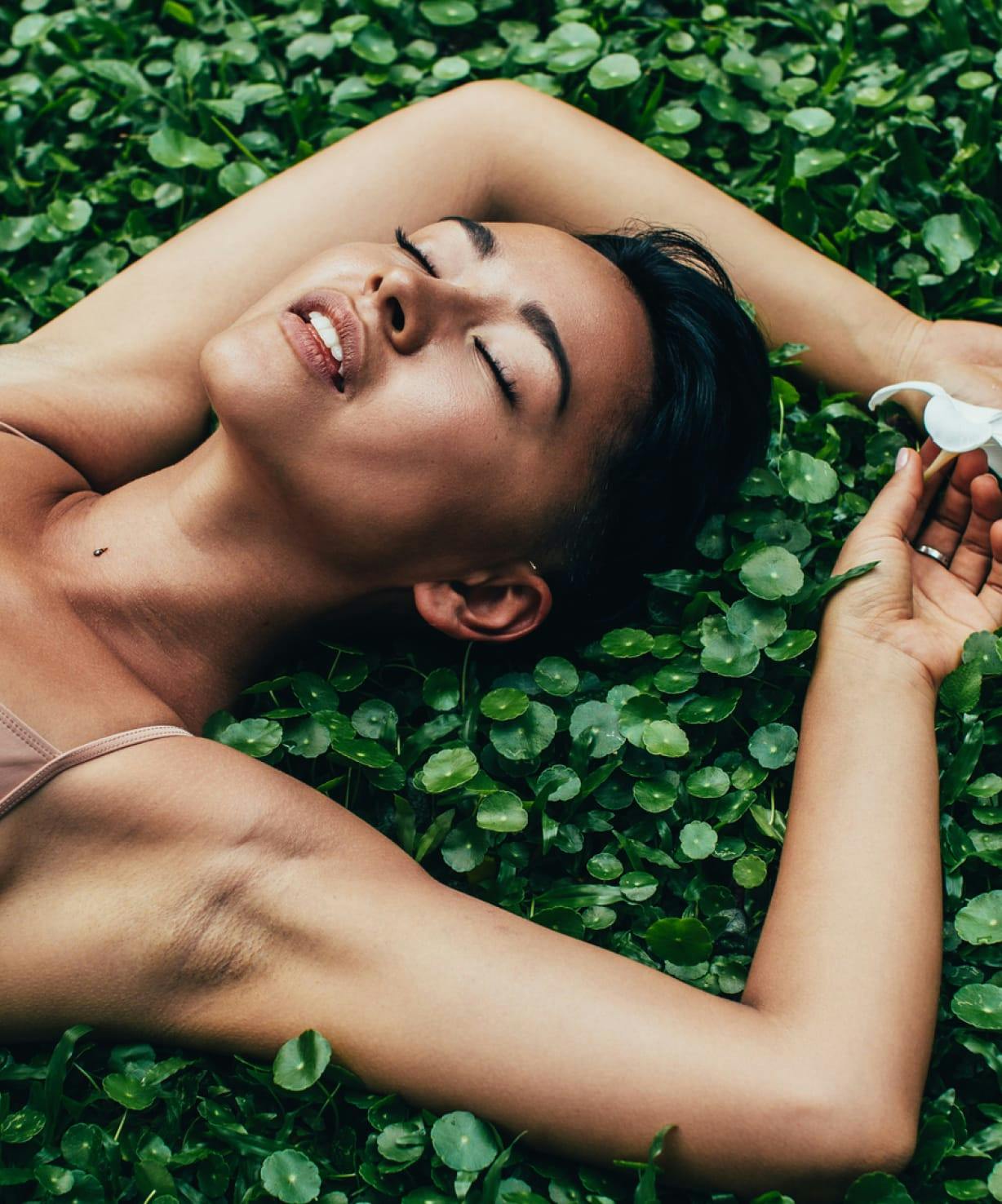 Woman lying on a bed of plants