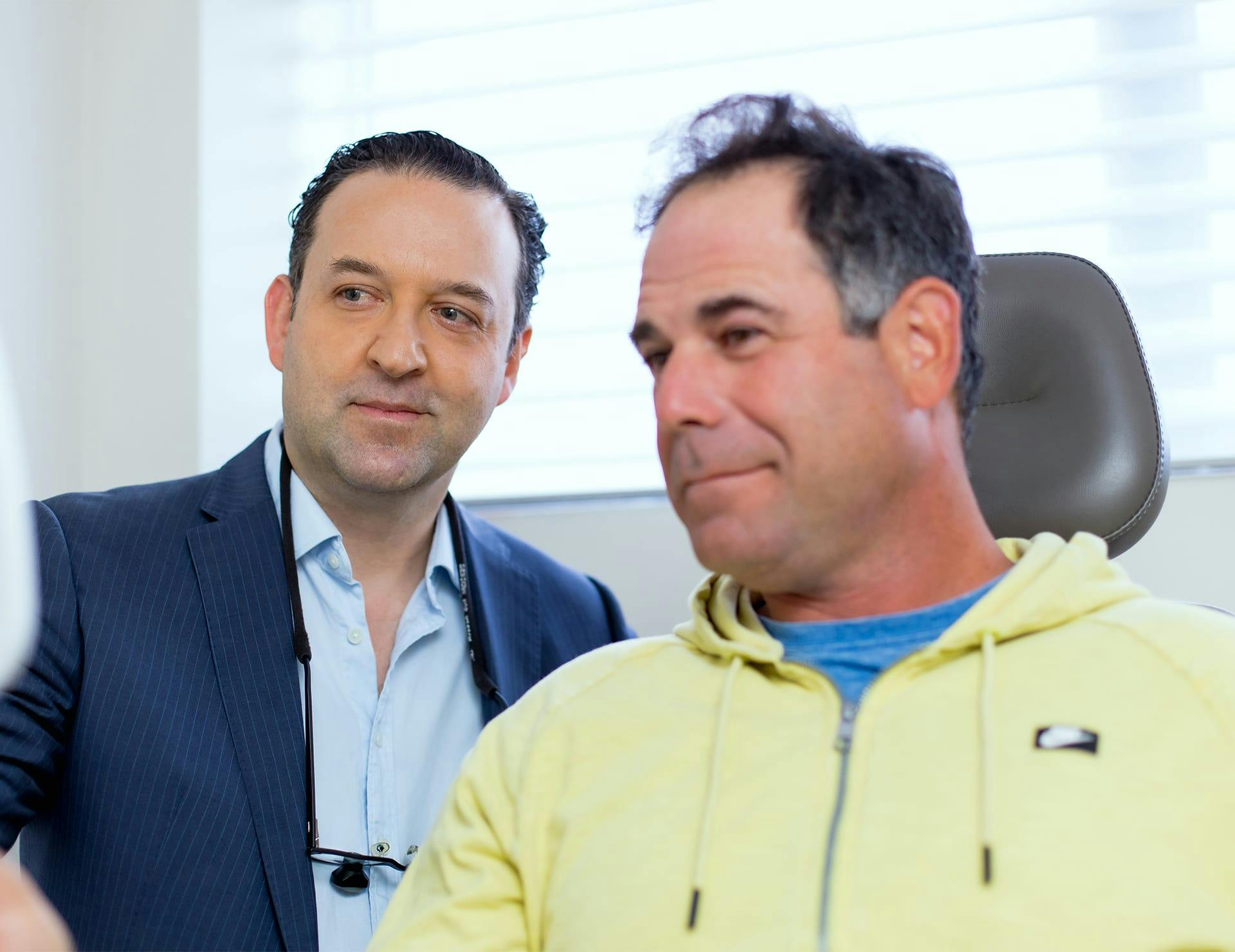 male client looking in mirror with doctor next to him