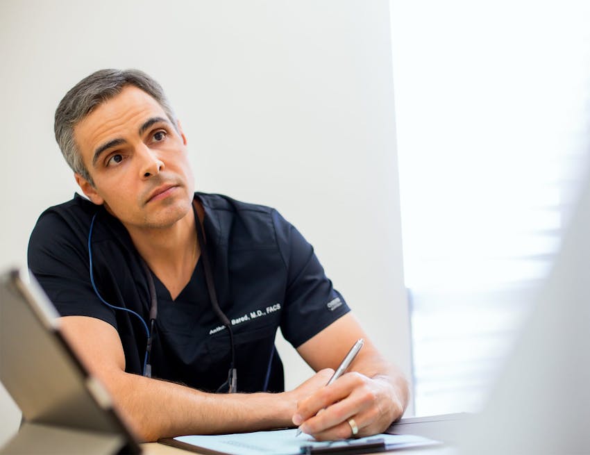 Dr. Bared signing paperwork while sitting down