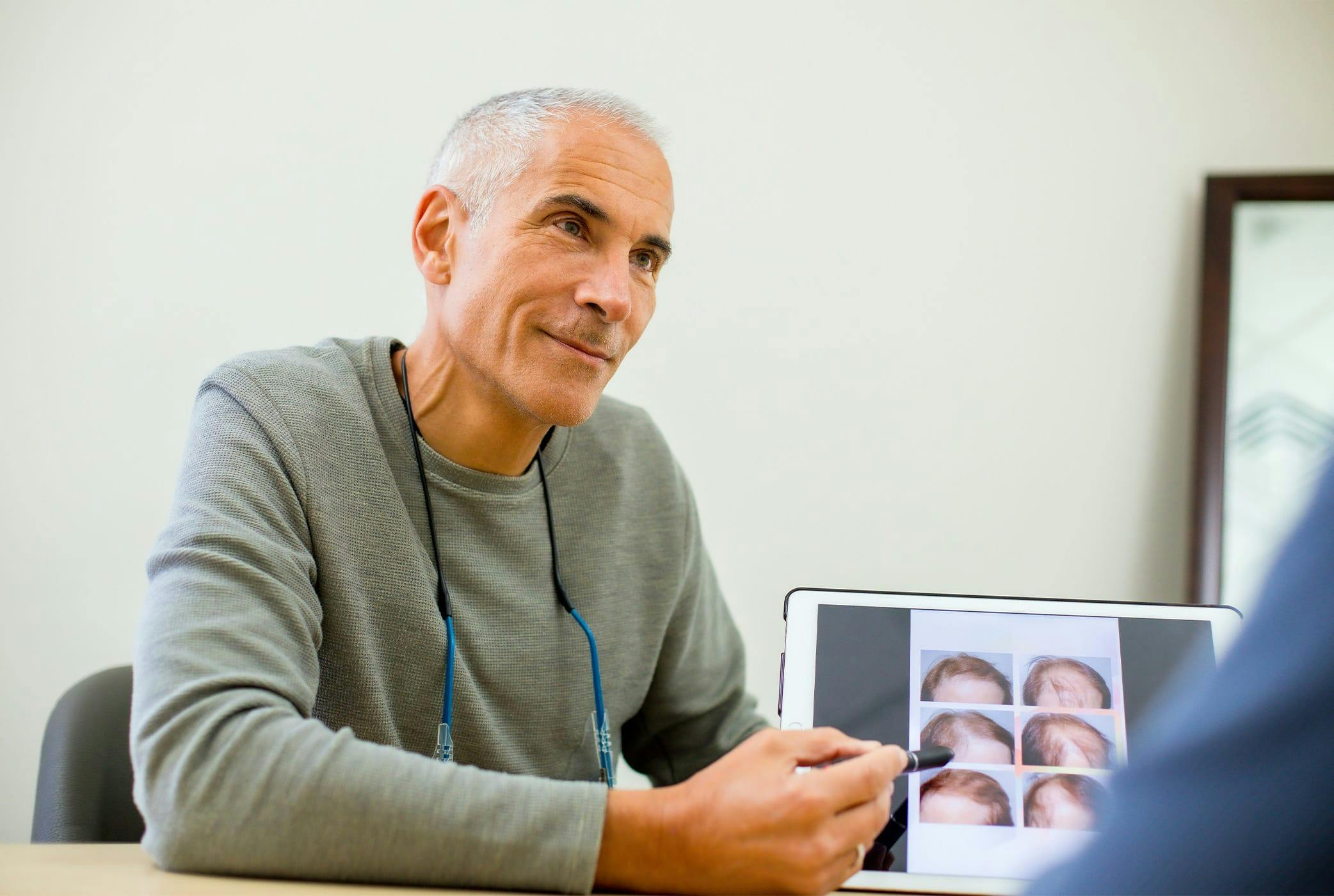 Jeffrey sitting and pointing to ipad thats showing before and afters