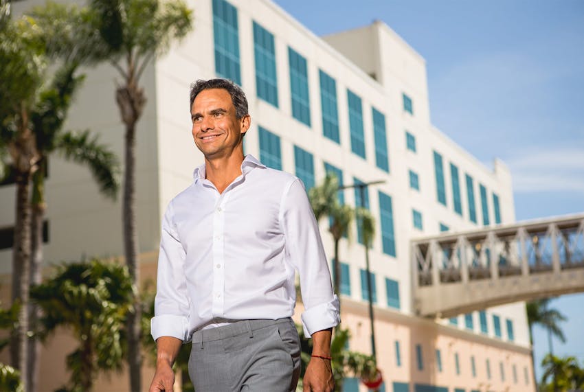 man walking while smiling with building behind him