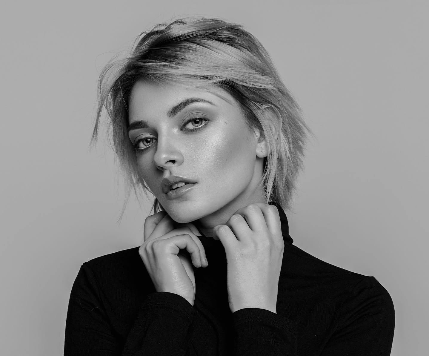 young woman looking at camera holding turtle neck