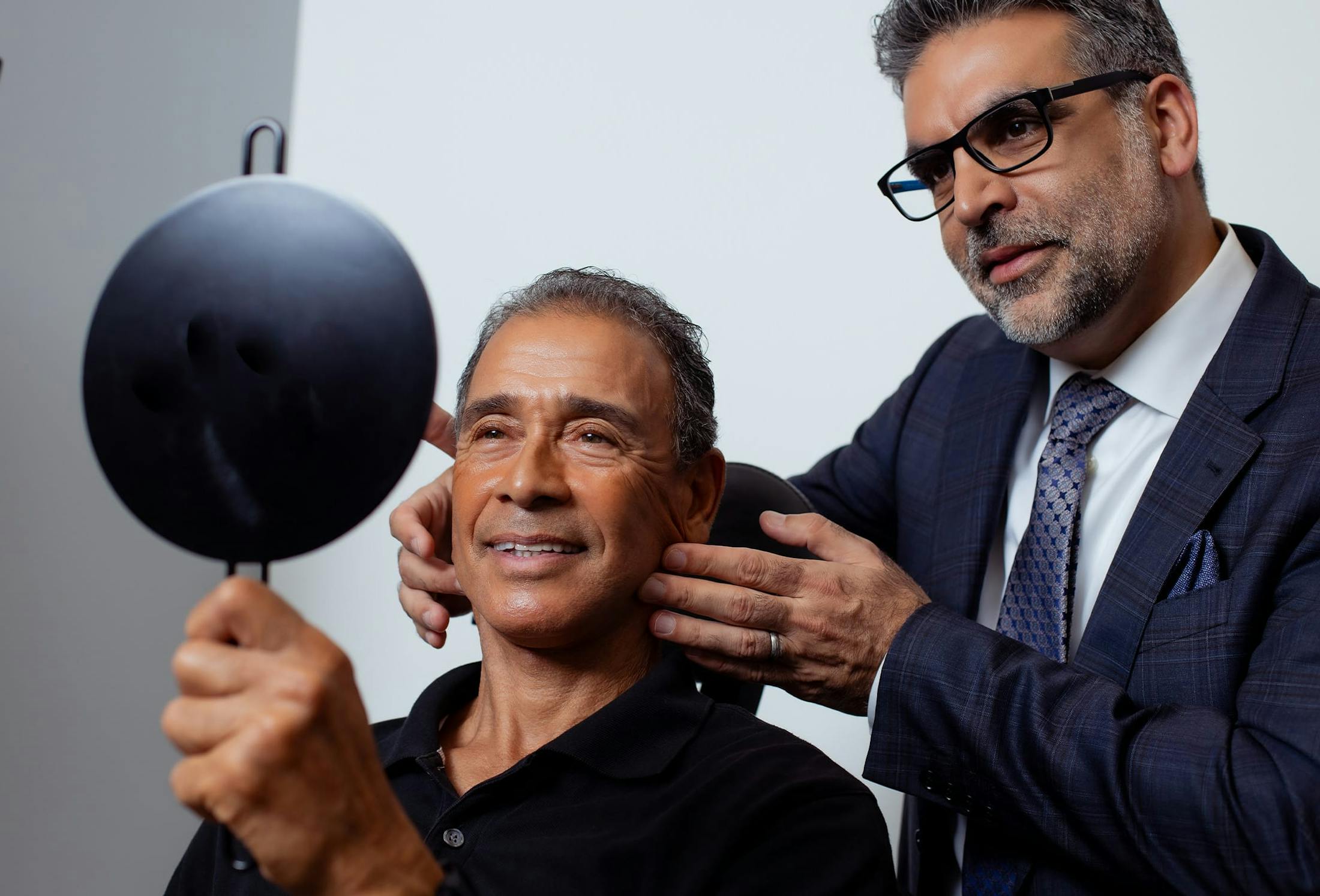man looking at his results in a hand mirror