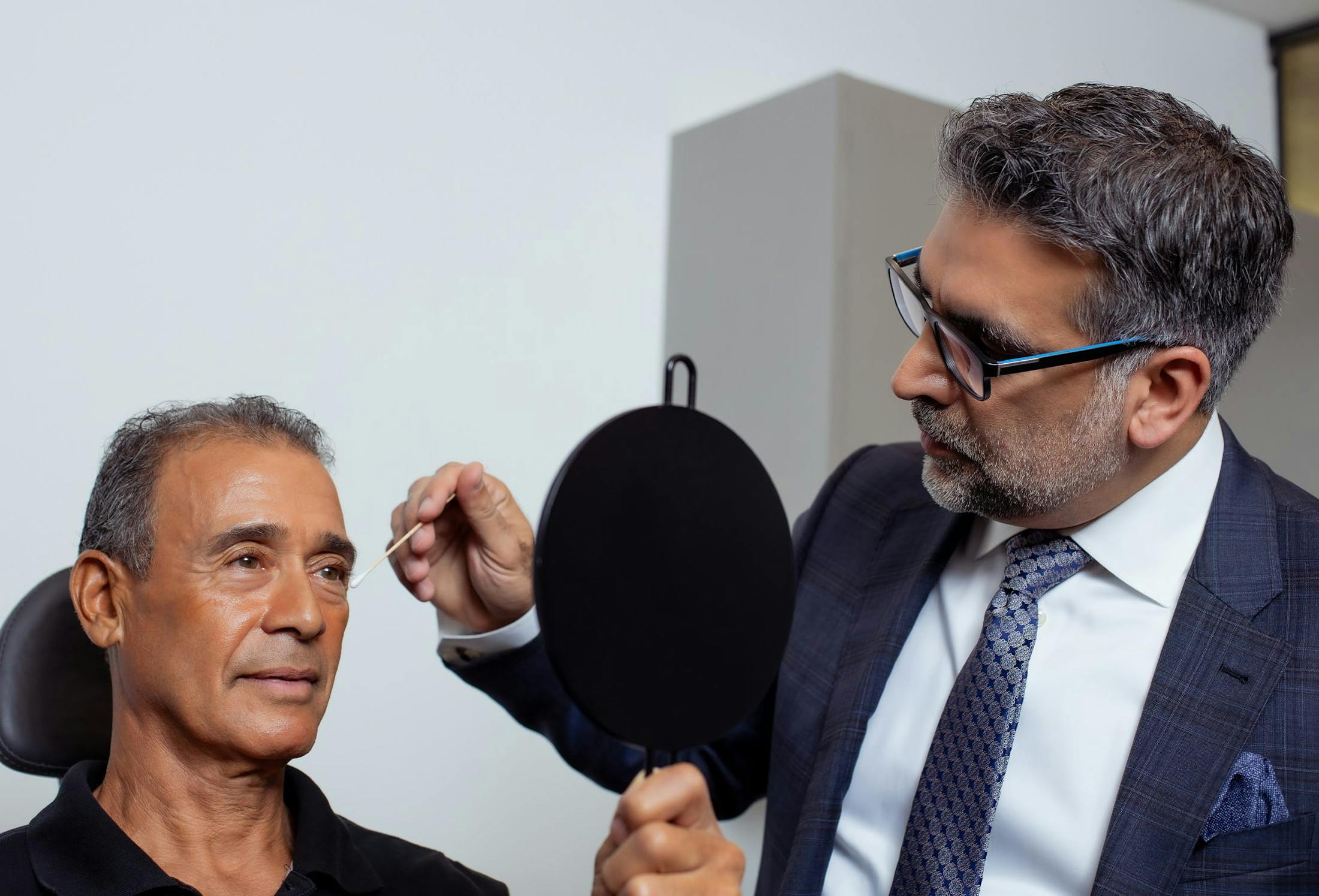 man looking into a hand mirror