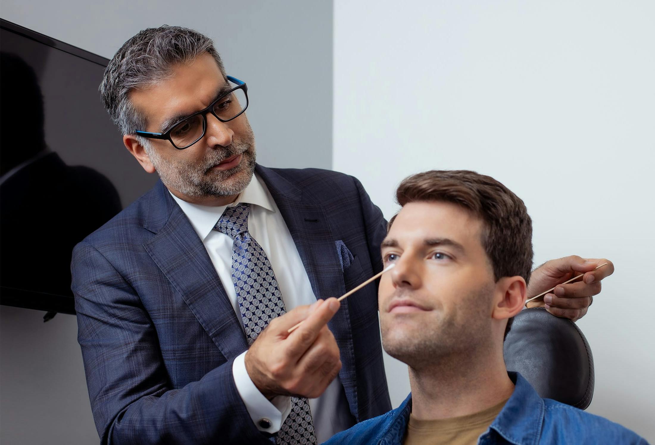 doctor touching male patients face with qu-tip