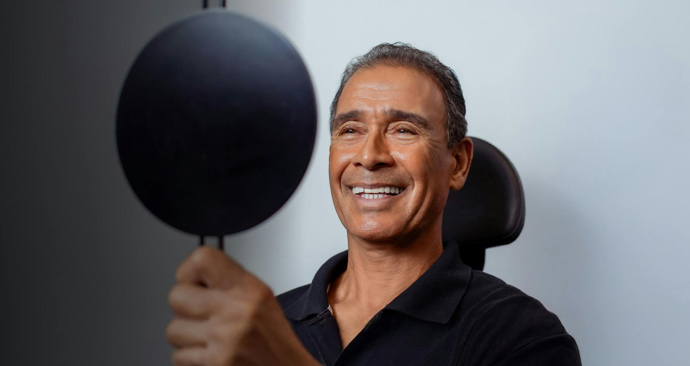 man looking at himself in a handheld mirror