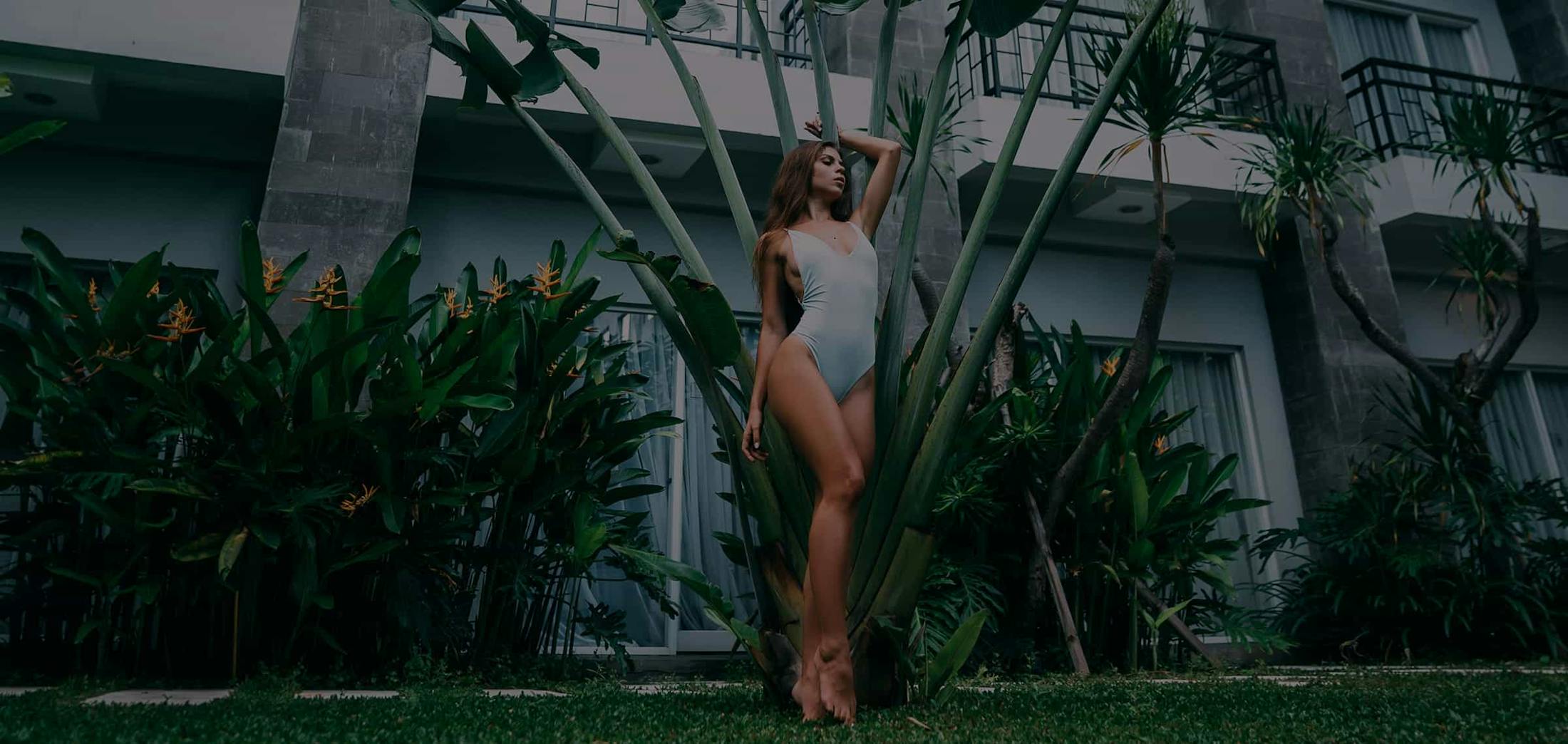 Woman leaning against a tree in a bathing suit