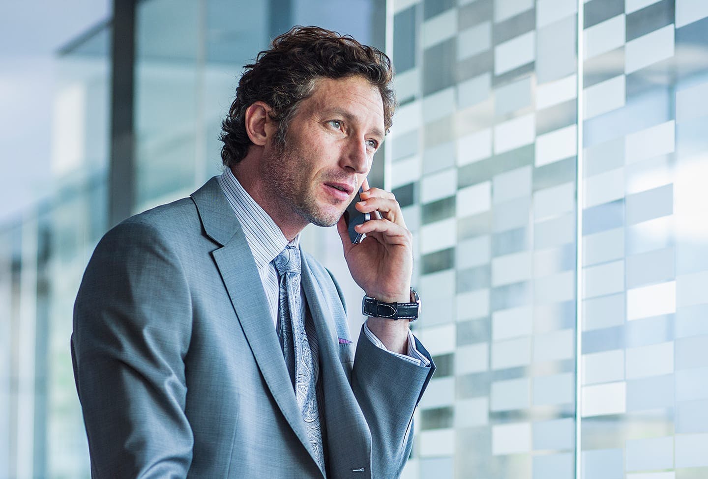 Man talking on a phone while looking out window of building
