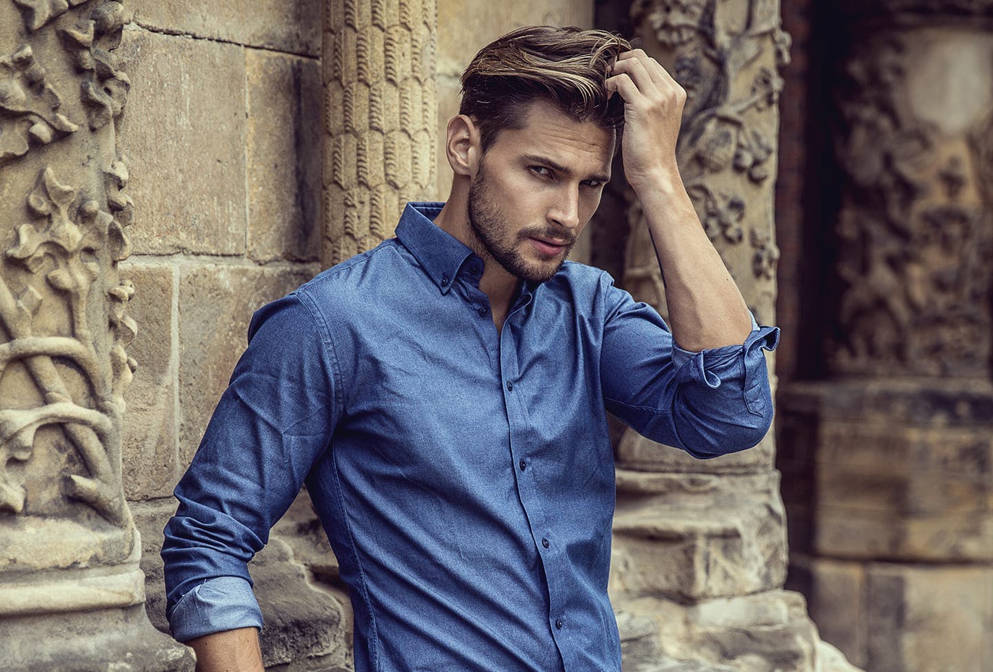 Man leaning against a wall with his hand in his hair