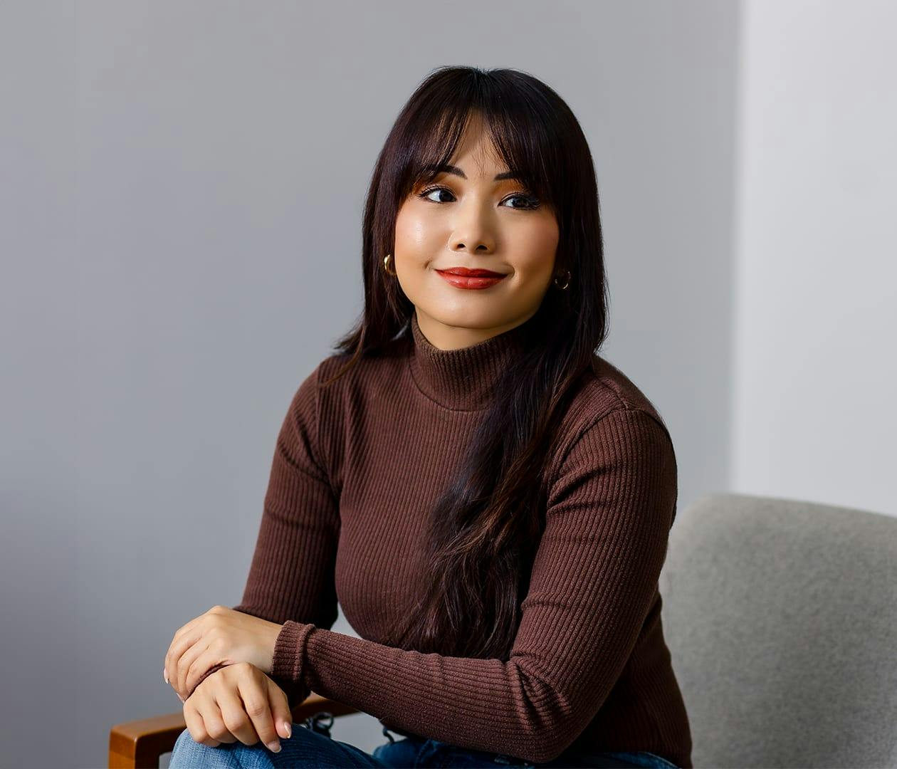 woman sitting in seat with both hands resting on her knee