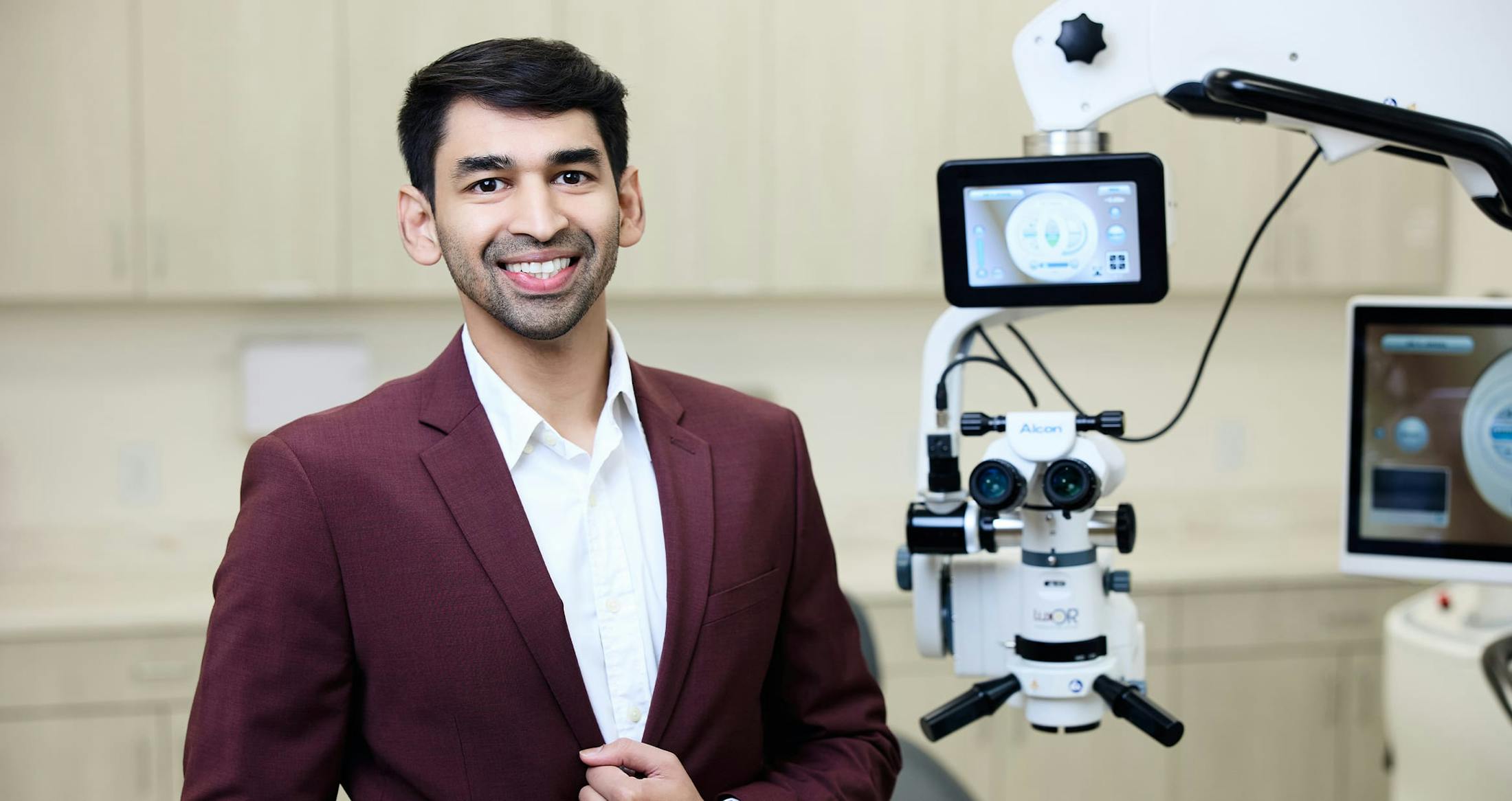 Doctor smiling next to eye equipment