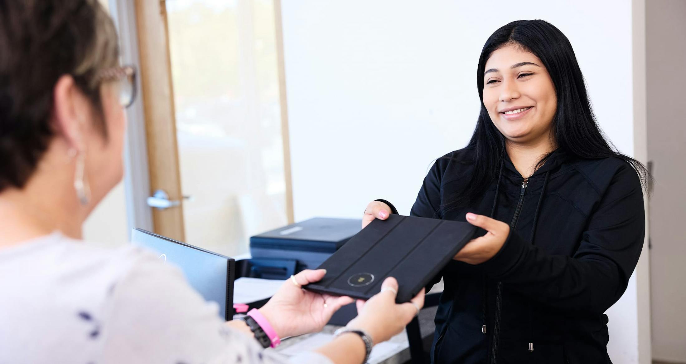 Woman smiling handing in tablet
