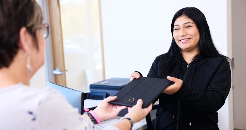 Woman smiling handing in tablet