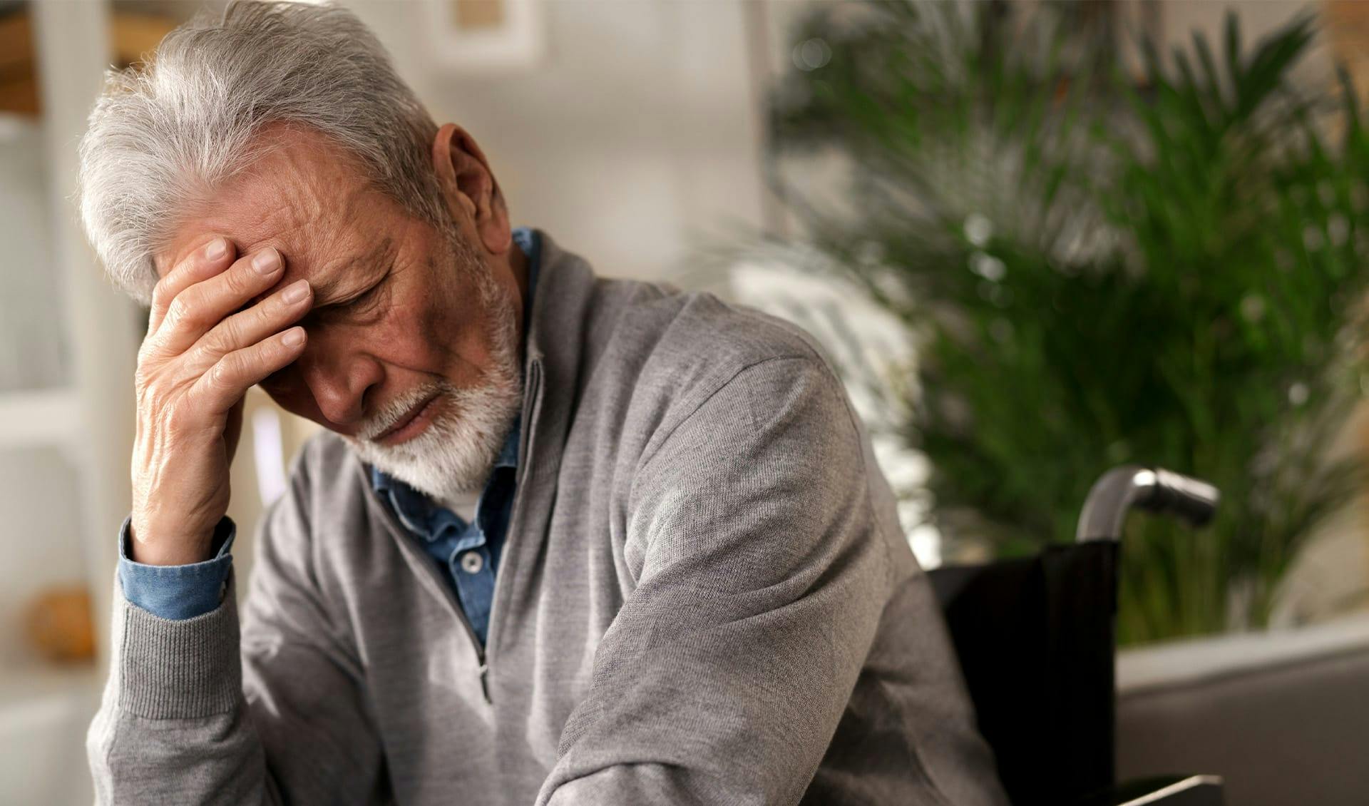 Older man holding head in hand