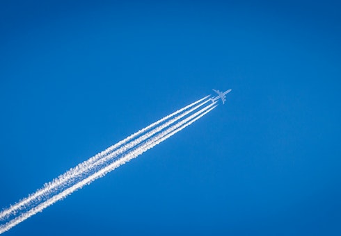 white airplane flying under the blue sky