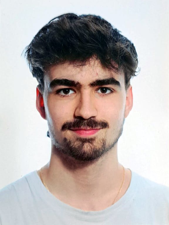 Porträt Porträtfoto eines Mannes mit dunklem Haar, Schnurrbart und Bart, blauem T-Shirt vor weißem Hintergrund