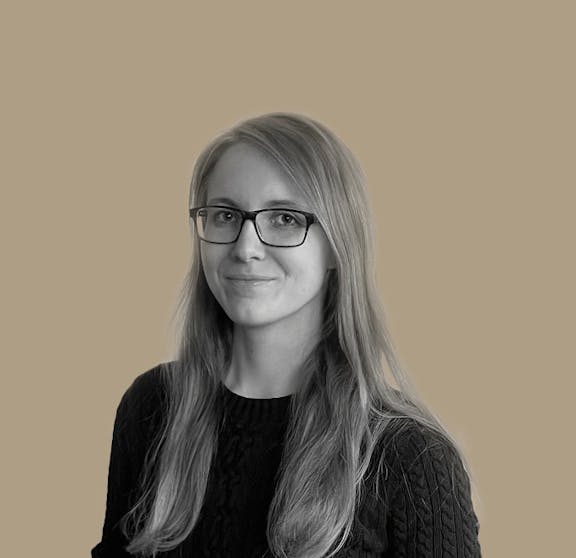 Team Portrait Portrait photo of a woman with long hair wearing glasses and dark top against beige background