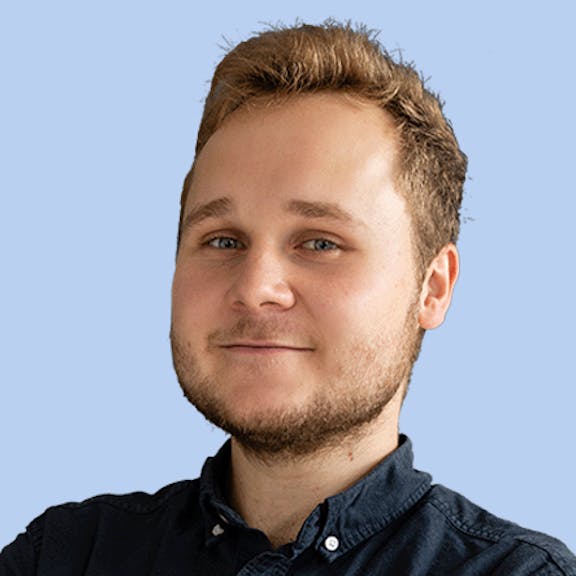 Portrait of a man with brown hair and beard against a blue background