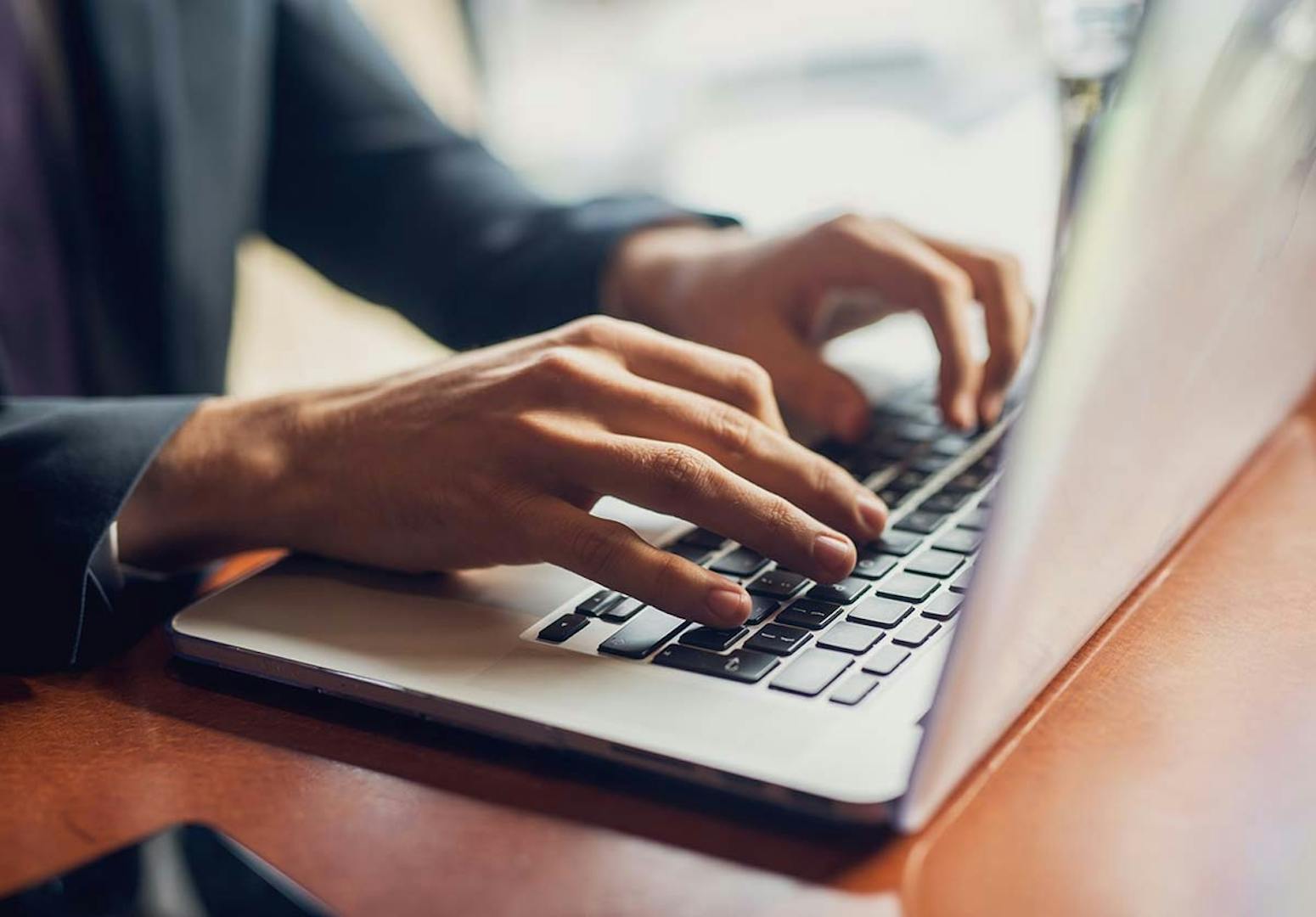 Working on a Laptop Person's hands typing on a laptop keyboard while working at a desk
