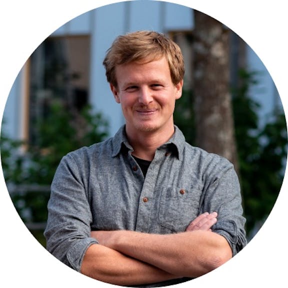 Kontaktperson Michael Porträt Portrait eines lächelnden Mannes mit verschränkten Armen in grauem Hemd vor unscharfem Hintergrund