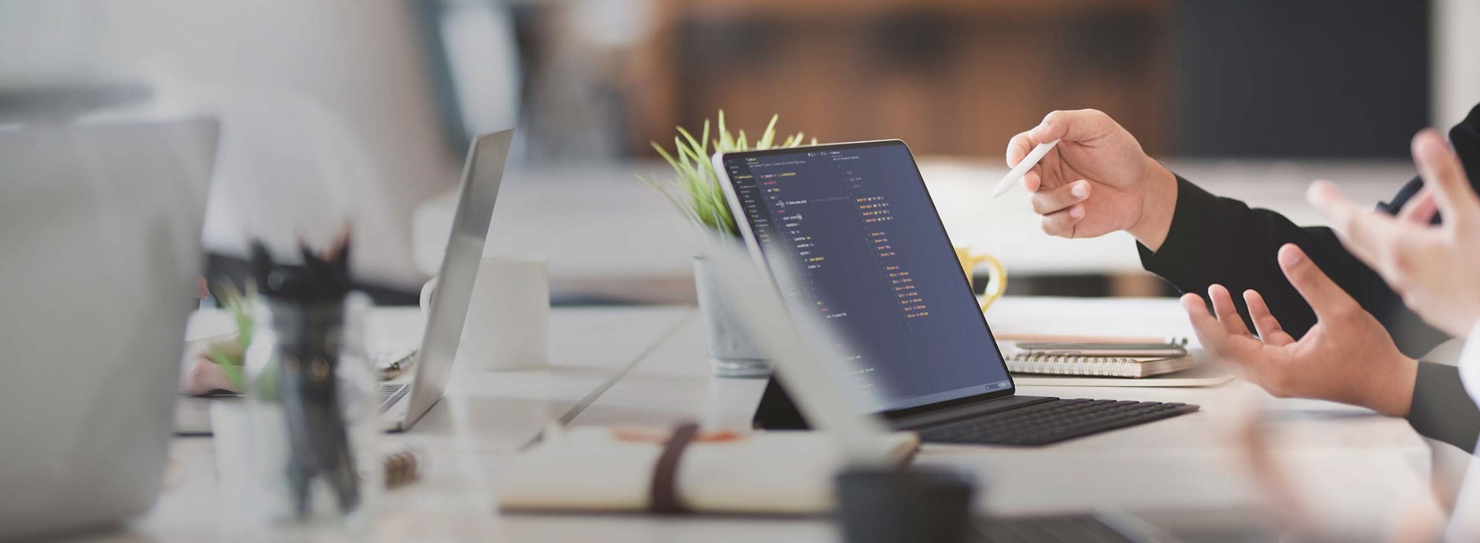 Entwickler zeigt Code auf Tablet-Display während Workshop-Diskussion im modernen Büro