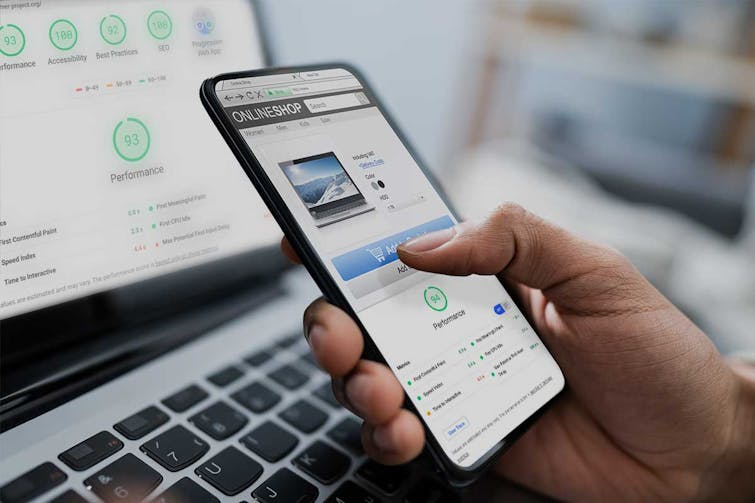 Person hält Smartphone mit Online-Shop-Website, im Hintergrund Laptop mit Performance-Metriken und grünen Scores