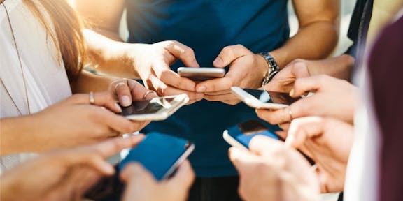 Group of people holding smartphones together looking at screens, symbolizing collaborative voting and digital participation