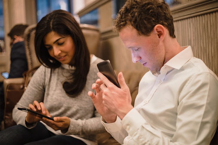 Zwei Personen schauen gemeinsam auf ein Tablet-Gerät in einem modernen Büro oder Besprechungsraum.