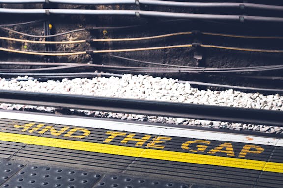 Close-up of a freight rail car with yellow GATX lettering, white ballast stones, and steel construction