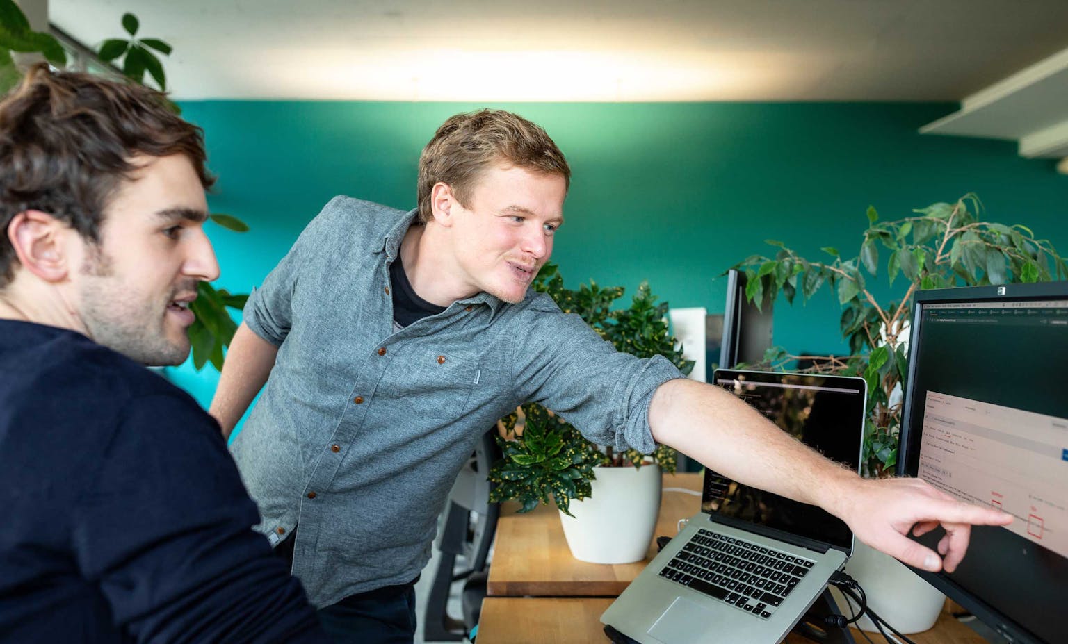 Zusammenarbeit im Peerigon Entwickler-Team Zwei Peerigon-Entwickler arbeiten gemeinsam an einem Laptop in einem modernen Büro
