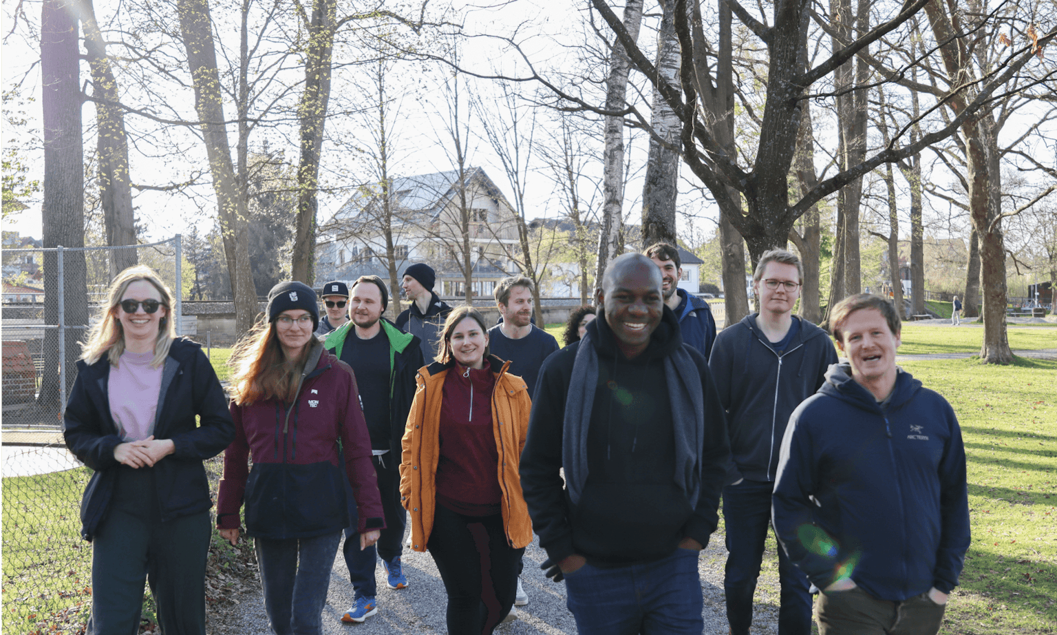 Team on a Group Walk Through the Park Group of Peeris walking together on a park path lined with bare trees, during a team event