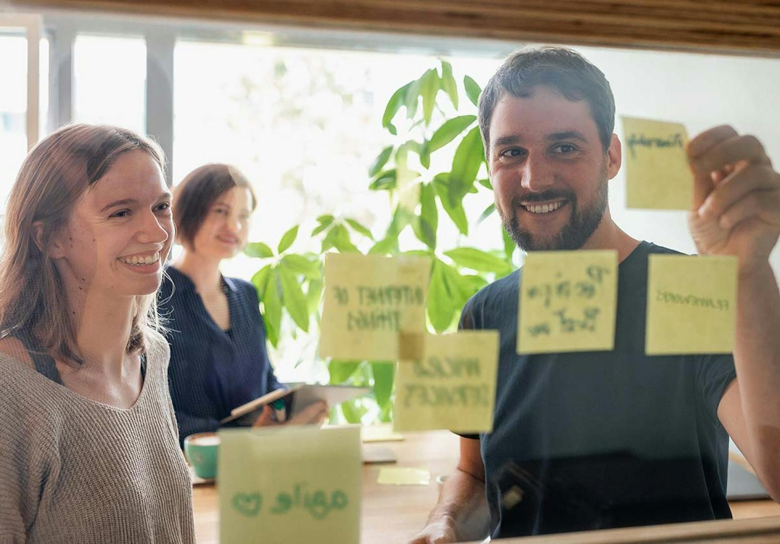 Peerigon Facilitatoren collaborating on a product sprint with sticky notes on glass wall