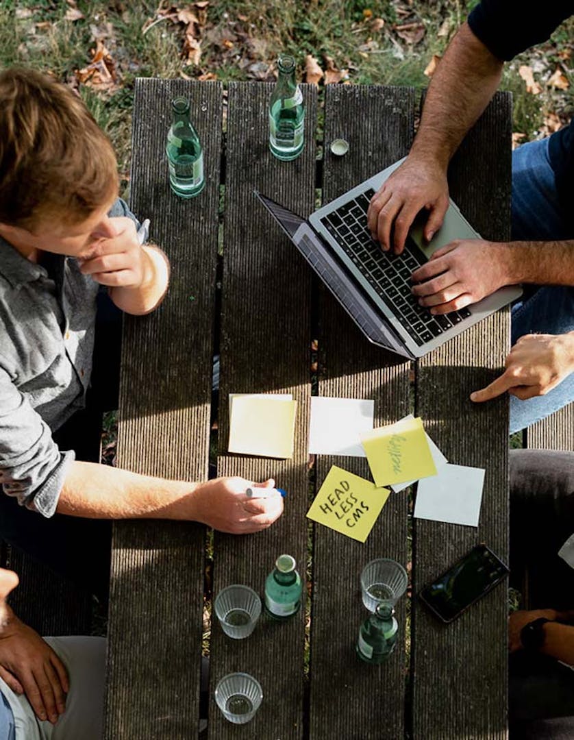 Group of Peeris collaborating at an outdoor wooden table during a workshop session