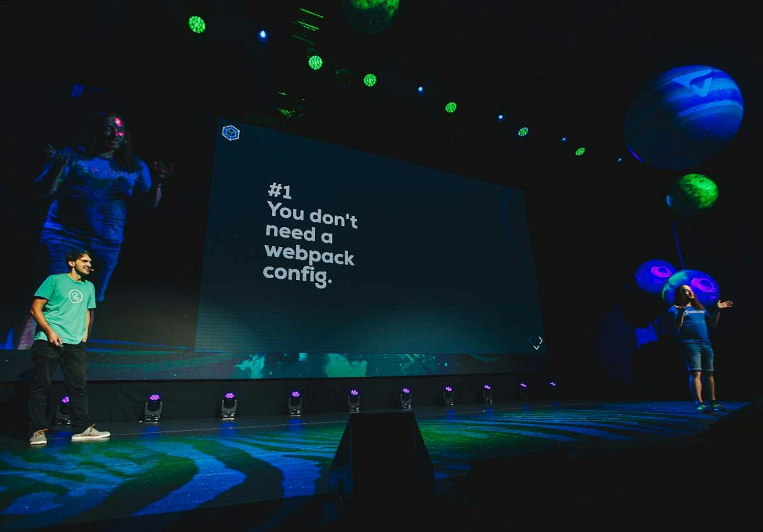 Johannes von Peerigon präsentiert auf der Prager React Conf eine Folie mit dem Text "#1 You don't need a webpack config." in einem dunklen Veranstaltungssaal