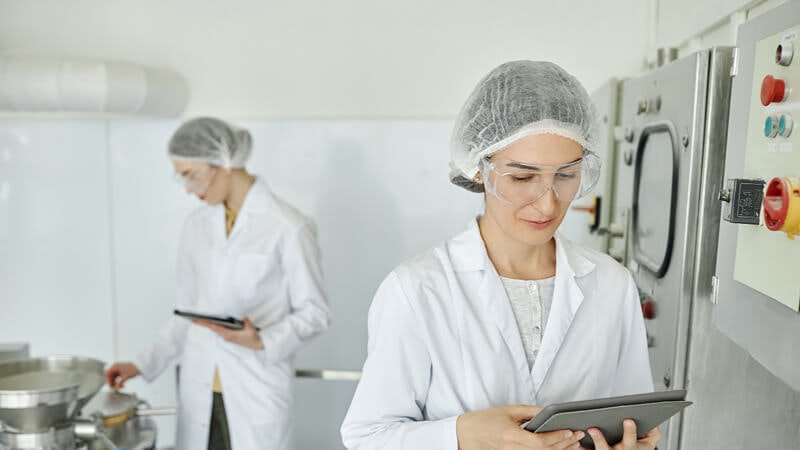 Auditor holds tablet in manufacturing facility.