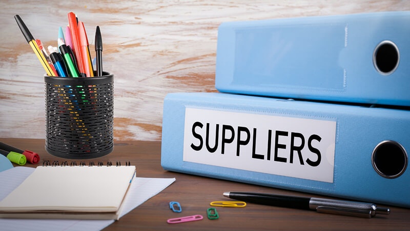 Binder marked supplier on desk with a lot of pencils around