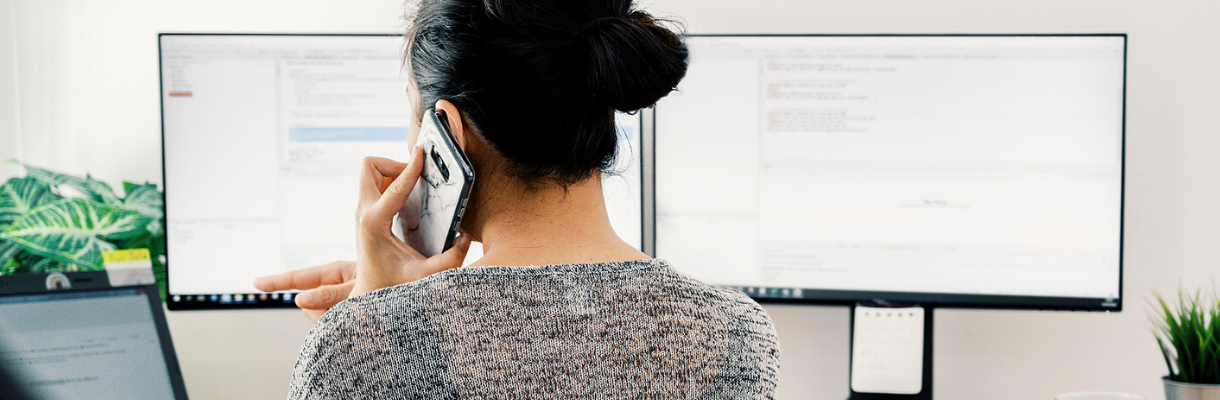 woman on phone with two screens