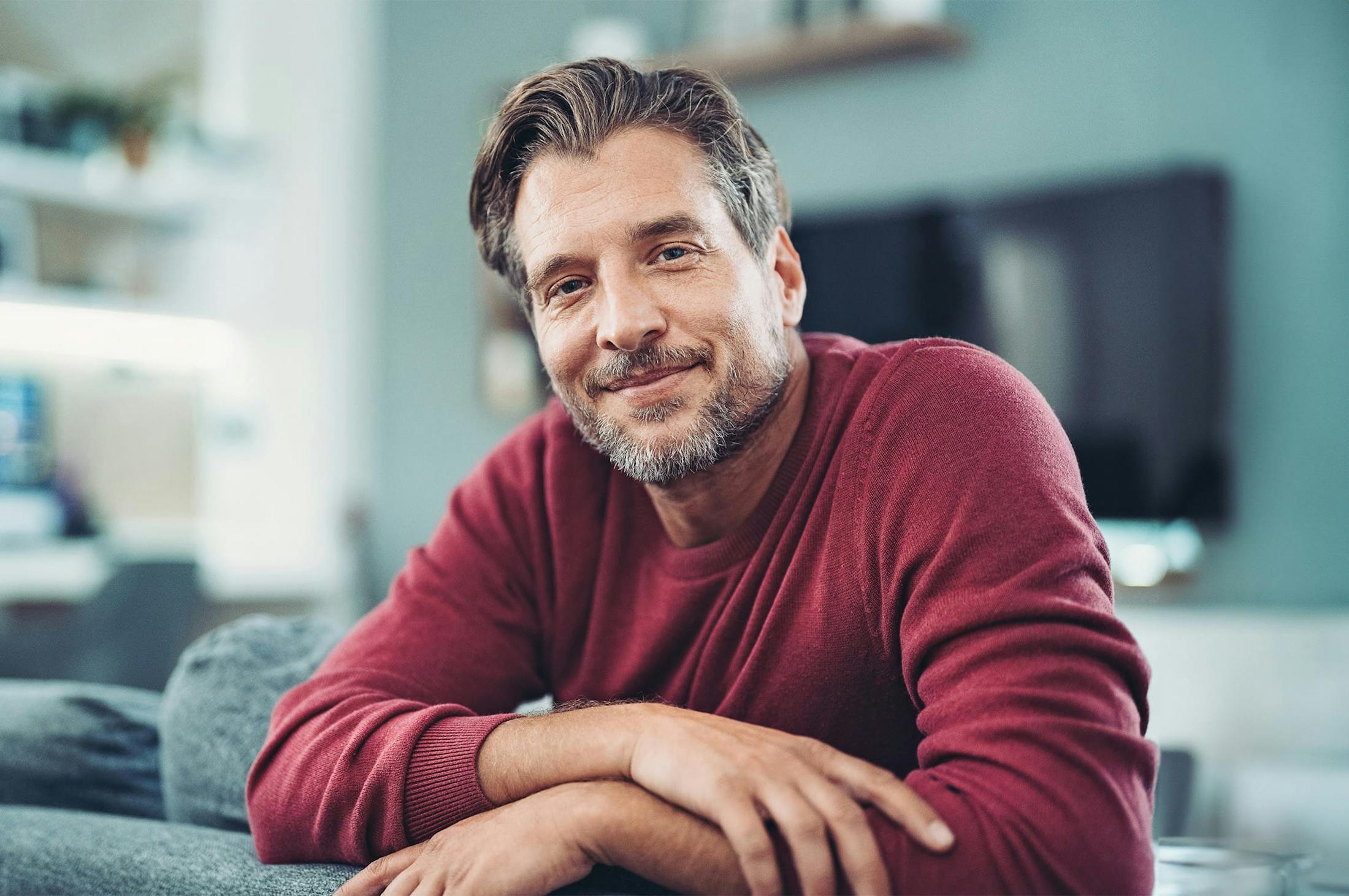 smiling man leaning over a couch
