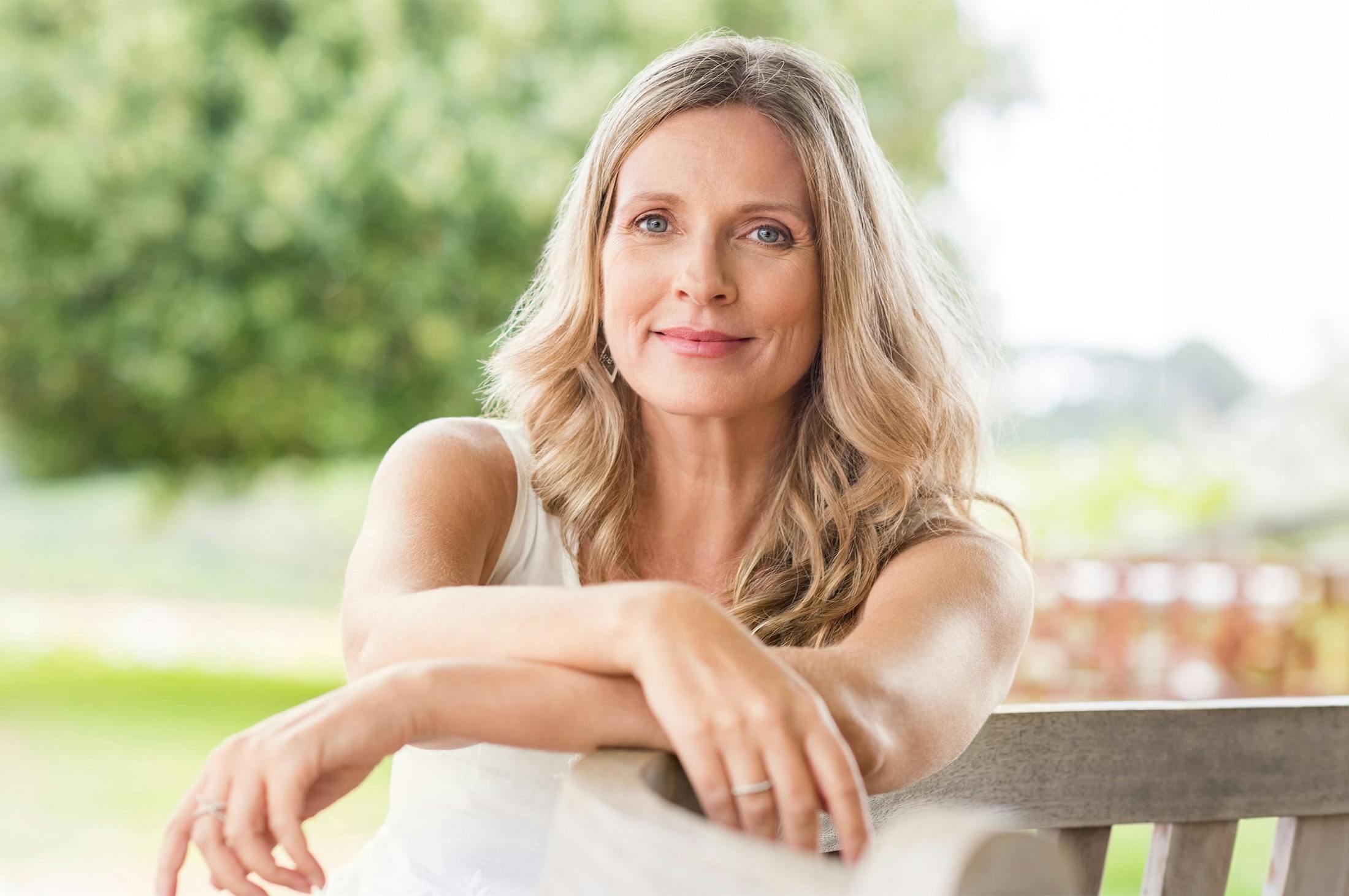 woman sitting on a bench, crossing her arms over the back rest
