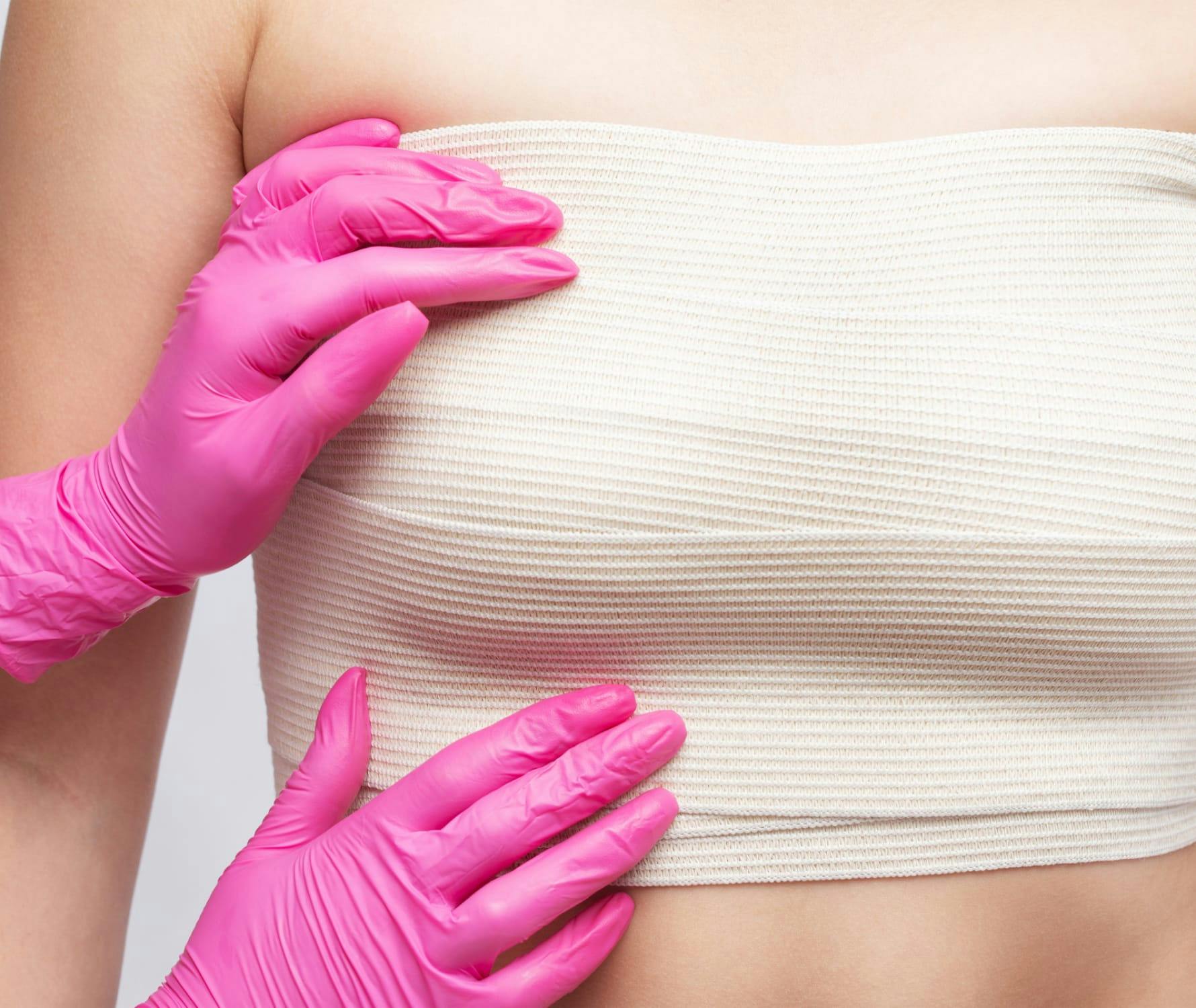 Close up of someone wearing surgical gloves touching womans breast