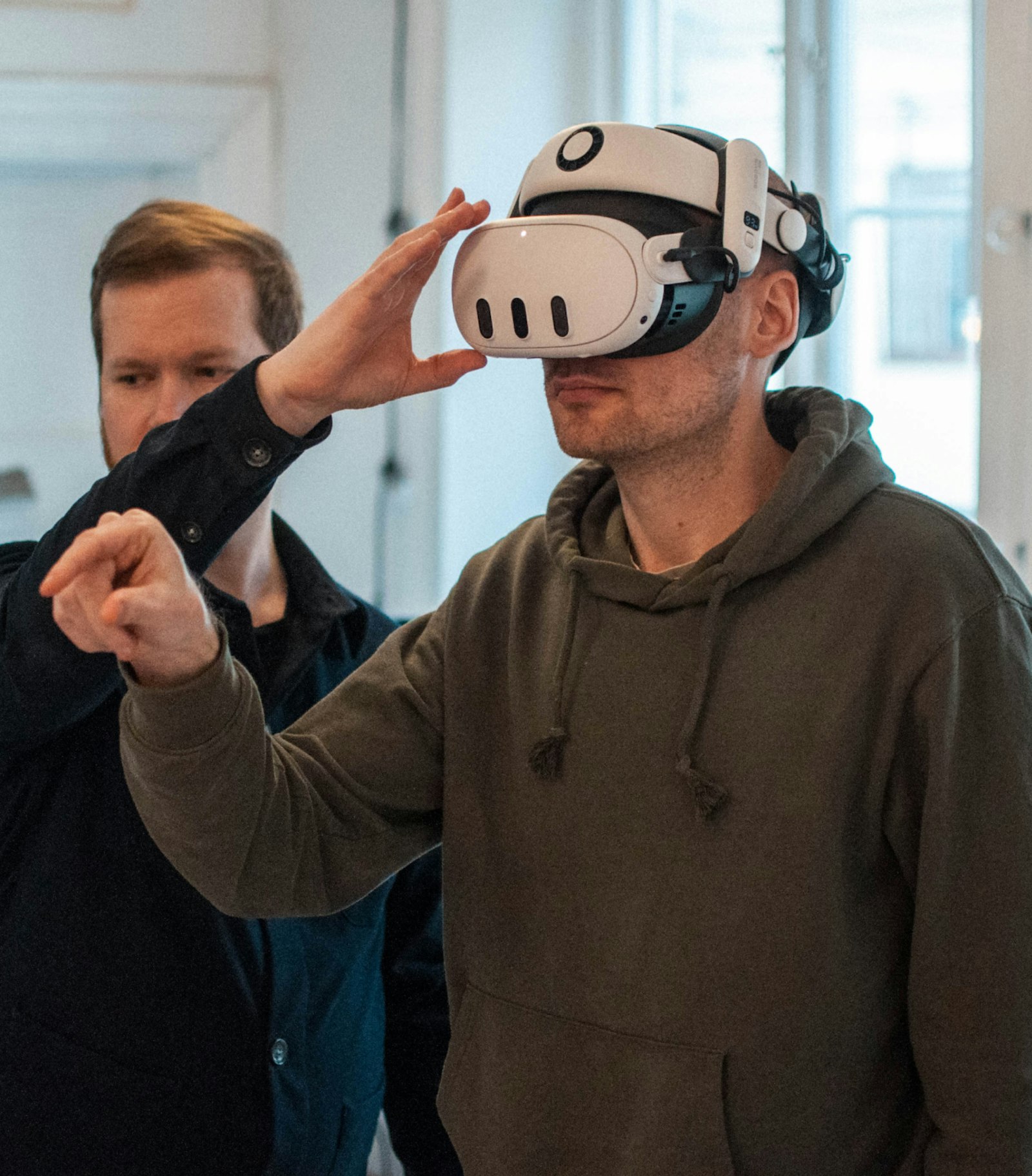 Person helping another person use a VR headset and headphones at an expo.