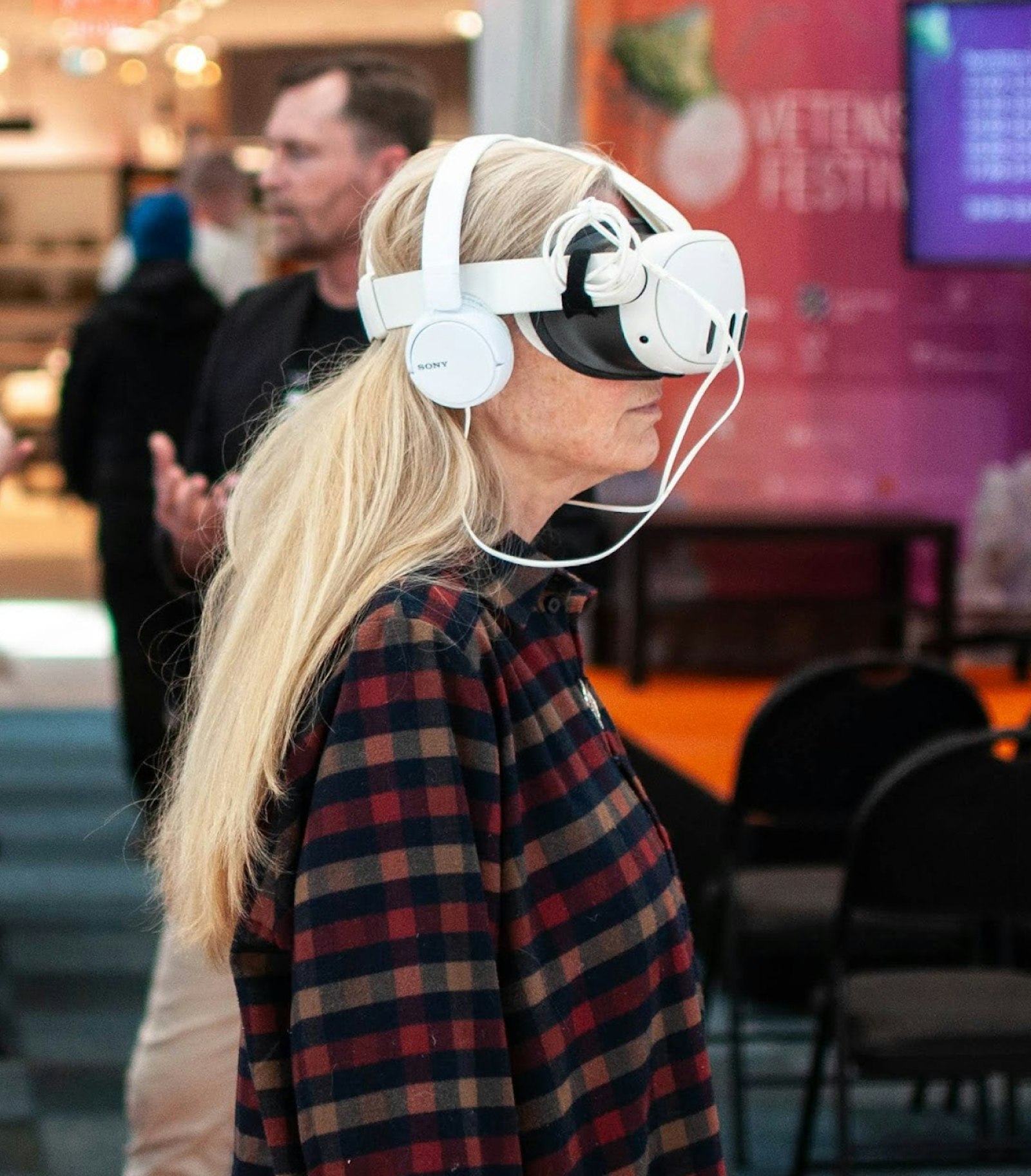 Woman wearing a VR headset and headphones at an expo.