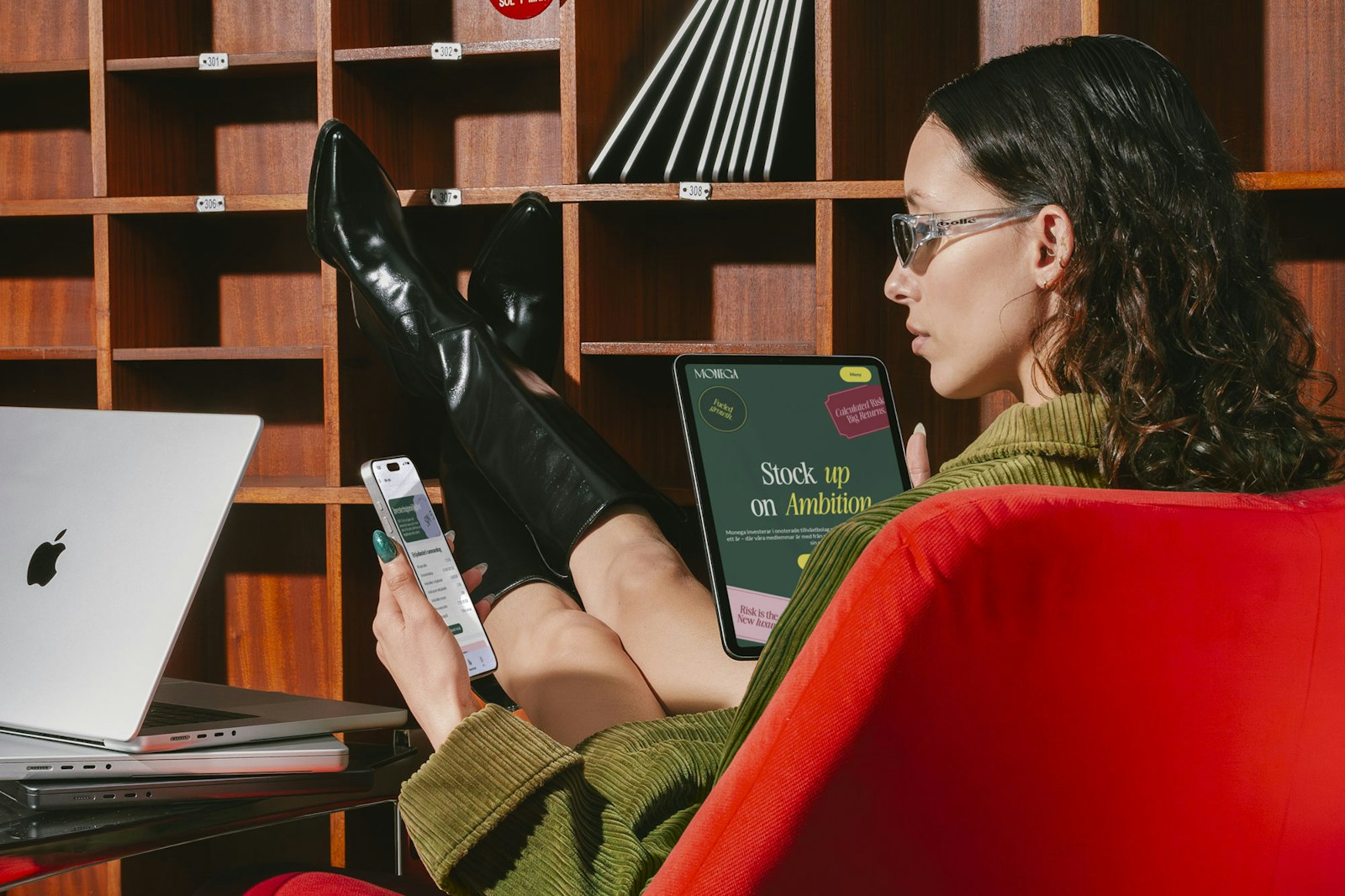Woman using laptop, tablet, and phone with Monega apps.
