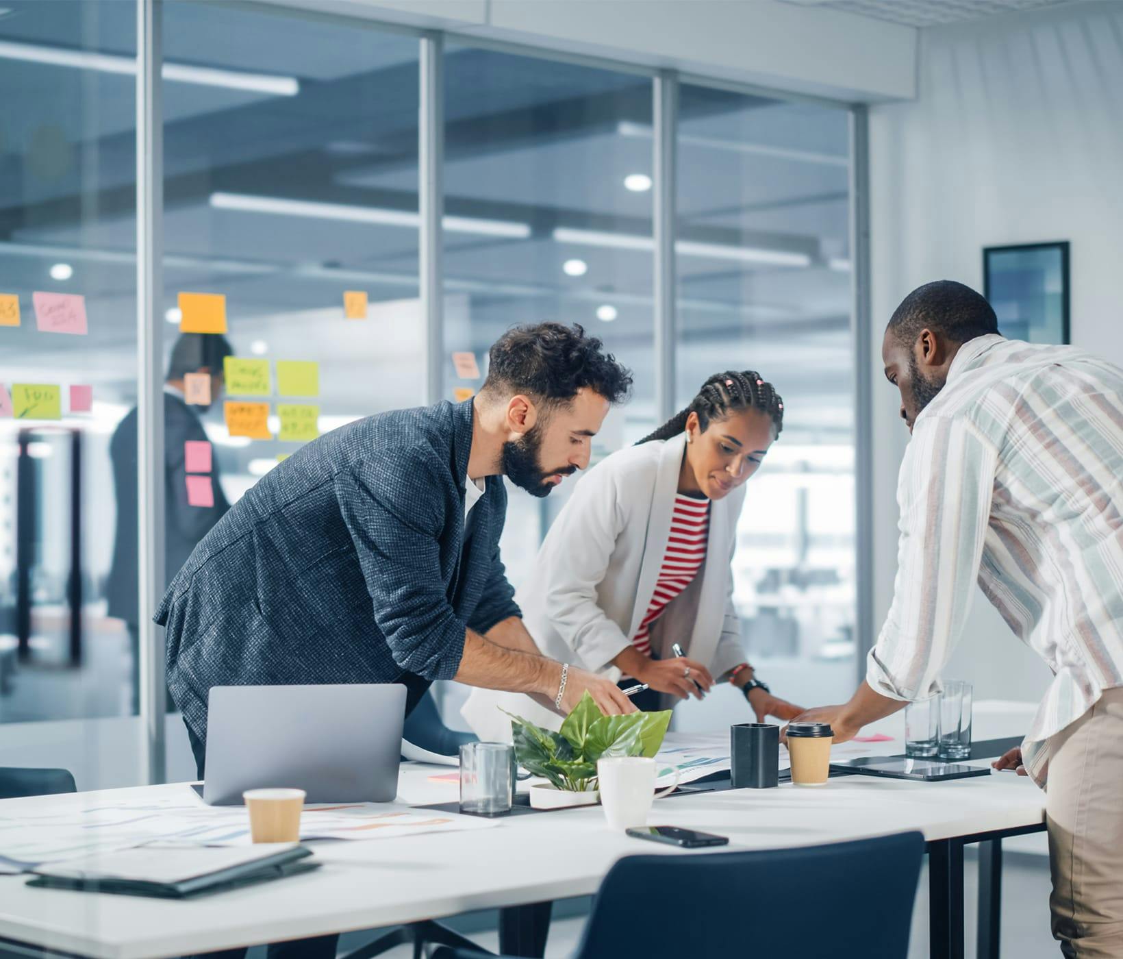 three people looking at paper work on a desk