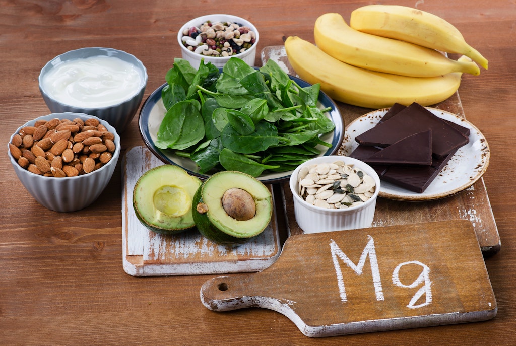 Nötter, spenat, avokado, bananer och mörk choklad bredvid en skylt med texten Mg